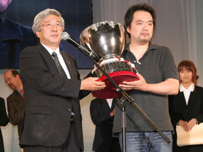 栄冠に輝いた平井昭臣氏(右)。佐藤慶喜JFTD会長からジャパンカップを手渡される