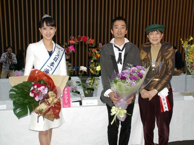 グランプリに輝いた岡田哲哉氏(中央)。(右)ヨシタミチコ理事長、(左)本選での岡田氏の花束を手にミス日本「海の日」