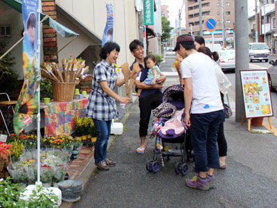 店頭でヒマワリ無料配布イベントを行ったフローリストナガイ